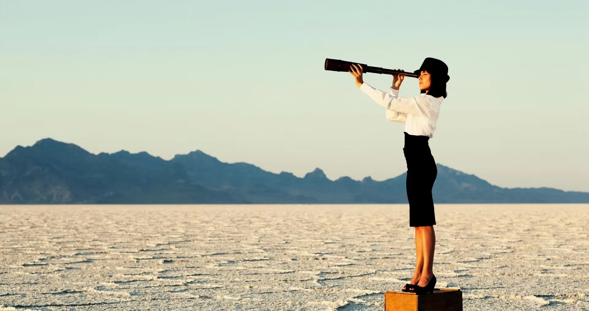 Femme observant l'horizon à la longue-vue, debout sur un lac salé